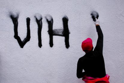 Una persona portadora de VIH pinta una fachada frente a la fiscalía de Ciudad de México con las siglas del virus de la inmunodeficiencia humana