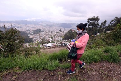 María Sangucho camina por una trocha desde donde se mira la mancha urbana del norte de Quito.