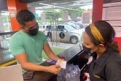 Joven presentando el carné de vacunación a la entrada de un gimnasio.