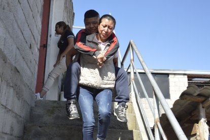 Doris carga en su espalda a su hijo para llevarlo a su terapia o a las consultas médicas.