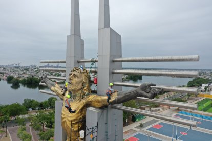 Carlos Ordóñez y Ricardo Durán, sobre los brazos del Cristo, y Daniel Aguirre, en el centro, en plena tarea de limpieza y restauración
