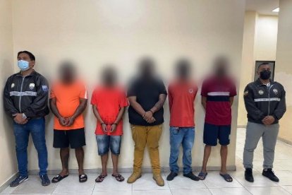 Dos policías escoltan a los 5 individuos arrestados en un operativo antidelictivo ejecutado en el suburbio de Guayaquil.