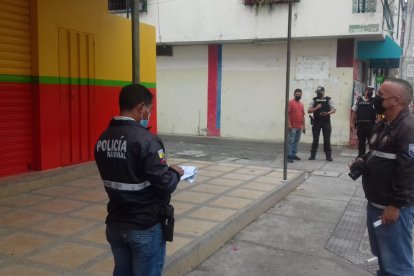 Agentes policiales recogen indicios en el sitio donde fue herido de bala un hombre.