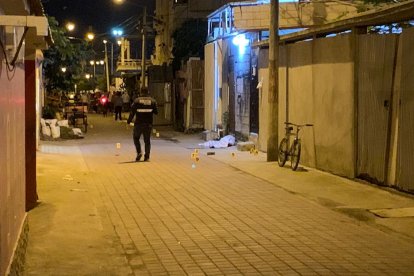 El cadáver de una de las víctimas yace al pie de la entrada de una vivienda, mientras un policía camina por el lugar.