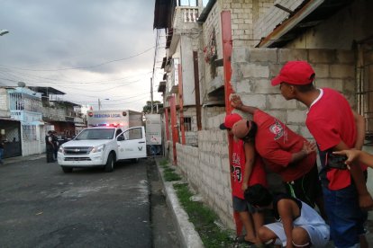 Vecinos de la víctima miran cautelosamente el arribo de equipos policiales a la escena del crimen.