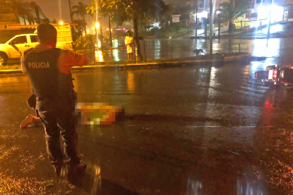 La víctima quedó tendida en la calzada mojada por la lluvia.