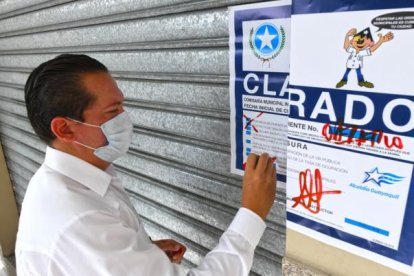 Un funcionario municipal coloca el sello de clausura a uno de los locales donde supuestamente hacían otros tipos de trámites.