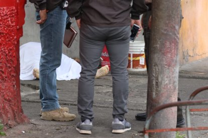 Agentes de Criminalística rodean el cuerpo del hombre asesinado junto a su negocio.