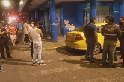 Policías junto al taxi que fue víctima de un ataque de hampones y donde la pasajera resultó muerta.