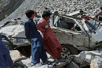 Personas observan el estado de la furgoneta luego de caer a un barranco y matar a 21 de sus 22 ocupantes.