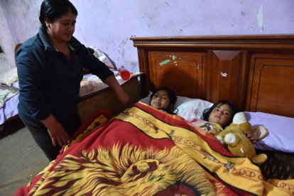 María Chiluisa recuesta a las dos niñas que están bajo su cuidado.