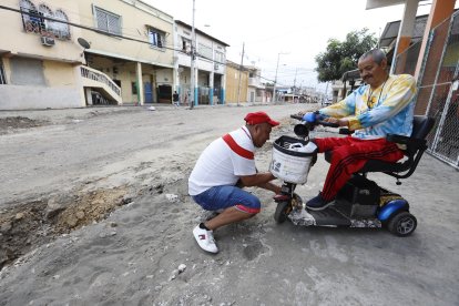 Antonio Cedeño (izq.) ayuda a su padre de 70 años para salir de la tierra en el que cayó,