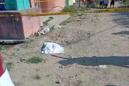 Una de las cabezas de un hombre sobre la esquina de una calle sin asfaltar.