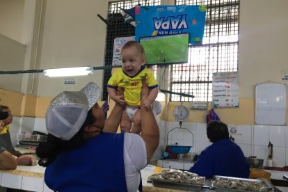 Lady Caicedo, comerciante del Mercado Oeste levanta a su pequeño sobrino, Lian, alentando a la Tricolor.