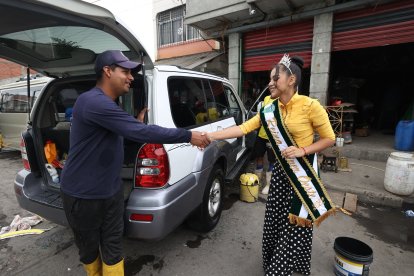 Un trabajador del lavado de vehículos en la zona detiene su actividad para saludar a la reina del club emblema de la barriada, el River Oeste.
