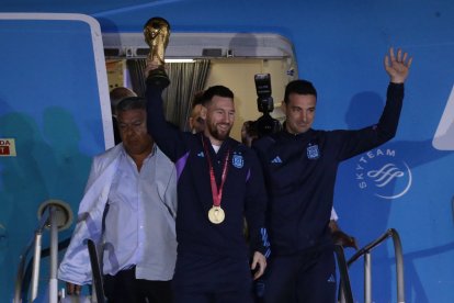Lionel Messi de la selección argentina de fútbol saluda con el trofeo del Mundial de Fútbol Qatar 2022 junto al seleccionador Lionel Scaloni (d) a su llegada, al Aeropuerto Internacional de Ezeiza.