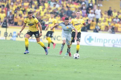 El uruguayo Bruno Piñatares (i) y Damián Díaz (d), argentino nacionalizado ecuatoriano, de Barcelona, pelean el balón con el gaucho Víctor Figueroa (c), de Aucas.