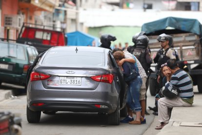 La progenitora del joven llora  al ver el cadáver de su hijo. Familiares la consuelan.
