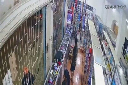 l criminal se acerca al negocio y se dirige a la víctima.  Tenía un papel en su mano.