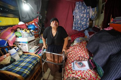 La mujer utiliza un andador para desplazarse en su cuarto estrecho.Mariana usa la misma cama para hacer tareas.