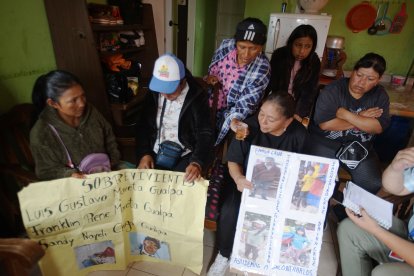 Las dos familias de los 11 migrantes muestran los carteles con las fotos de sus seres queridos.