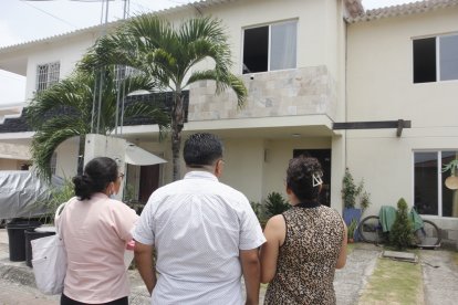 Vecinos observan, consternados, la casa donde el lunes 20 de marzo tres miembros de una familia murieron intoxicados.