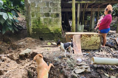 María Bravo recorre con su hijo en brazos el sitio donde el deslizamiento de tierra ha dañado parte de su casa en el cantón Muisne.