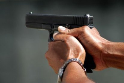 PISTOLA APUNTANDO Y SOSTENIDA POR DOS MANOS.