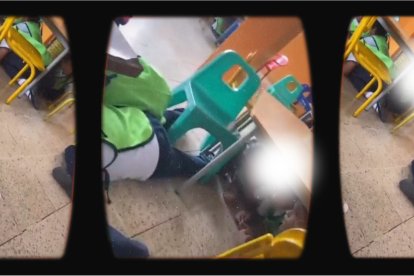 Los niños, por orden de la maestra, quien graba el video, se encuentran debajo de las pequeñas mesas de trabajo.