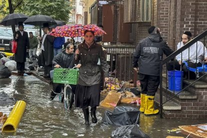 Peatones caminan por una vereda inundada el viernes 29 de septiembre de 2023, en el distrito de Brooklyn en Nueva York.