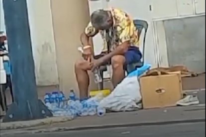 Momento en que El Gato, como es conocido el vendedor de agua, llena con líquido los envases usados.