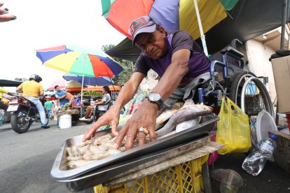 Desde su silla de ruedas, Arturo despacha el camarón, pescado o queso para sus clientes.