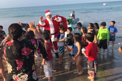 Decenas de niños recibieron a Papá Noel en la orilla de la playa, una vez que llegó en moto acuática.