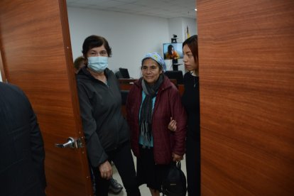 Eva Calva (chompa color vino) sale de la audiencia en contra de Stalyn Caiza, a quien se lo observa en el monitor que está detrás.