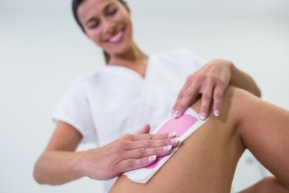 Woman getting her leg hair removed at beauty salon