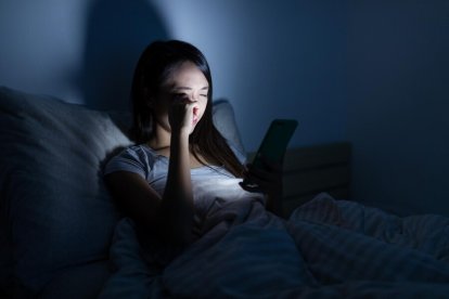 Chica de 14 años mira su teléfono móvil antes de dormir