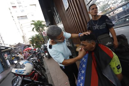 Darío corta el cabello en medio de la Bahía, al pie de una estación de Metrovía.
