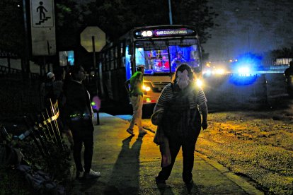 Los pasajeros esperan los buses en una oscuridad tenebrosa.