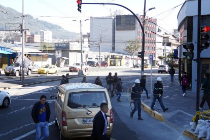 Algunos conductores, pese a la luz roja del semáforo y que peatones están cruzando, avanzan con sus vehículos.