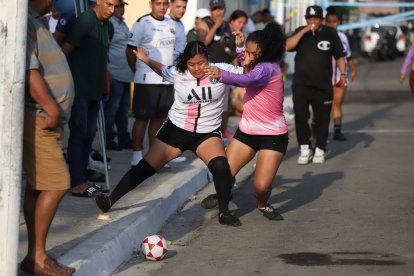 Dos jugadoras se disputan la pelota entre codazos y patadas.
