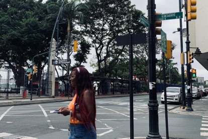 La ciudadana Ashly Cortés, entre el nuevo letrero de ‘República de Guayaquil’ y el antiguo de '10 de agosto'.