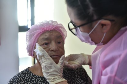 Robertina Moscoso siente alivio y se distrae mientras le aplican cremas para hidratar su piel. Ella vivió con cáncer por muchos años.