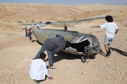 Curiosos observan los restos de un misil balístico en el desierto, tras un ataque de Irán contra Israel, cerca de la ciudad sureña de Arad.
