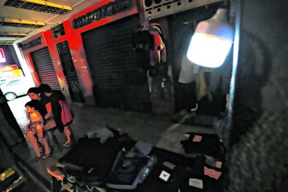 Un foco recargable ayuda a un comerciante ambulante a guardar su mercadería.