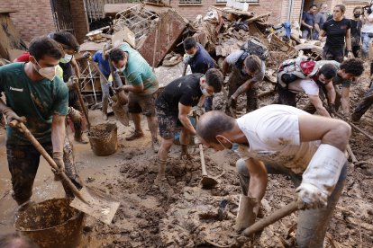 Voluntarios recogen los escombros y lodo arrastrados por las inundaciones.