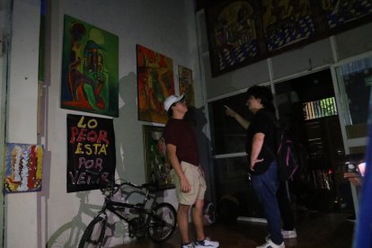 Visitantes tratan de contemplar los cuadros de la galería en la oscuridad.