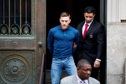 El peleador de artes marciales mixtas, el irlandés Conor McGregor (i), es escoltado mientars abandona una comisaria neoyorquina