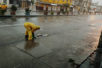 Ciudadanos utilizan fierros para destapar las alcantarillas para que el agua acumulada pueda desfogar.