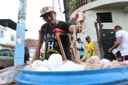 El hombre mantiene fresco su producto con bloques de hielo en una bandeja.