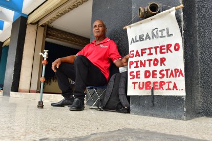 Alejandro Jama muestra un cartel donde detalla los tipos de trabajo que efectúa.